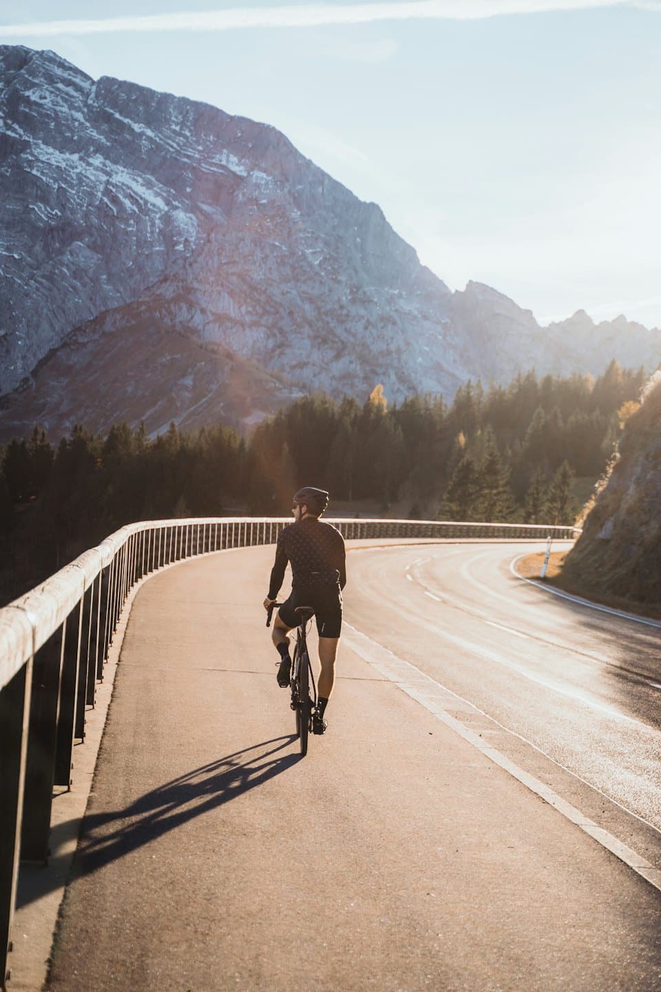 Cyklista jede na silničním kole po klikaté horské cestě.